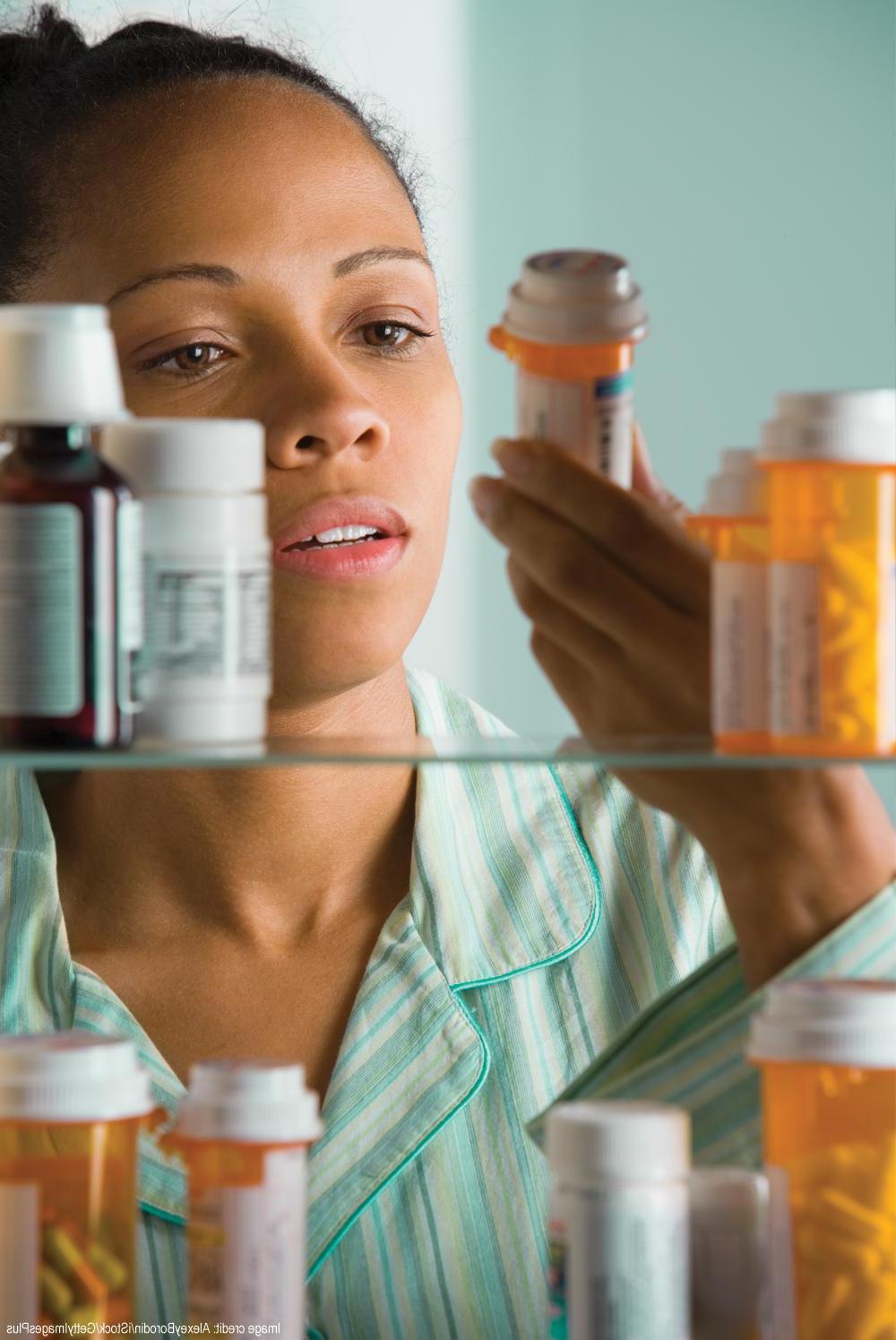 一名妇女在橱柜里检查药品的照片